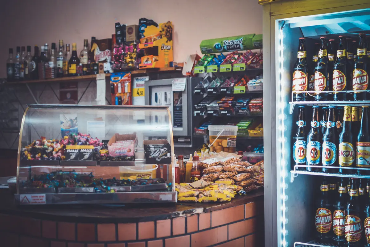 A convenience store counter with a candy case and a stocked drinks cooler — convenience store insurance in Delaware.